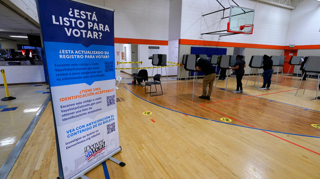 FILE - A sign in Spanish stands near voters as they cast their ballots at stations inside the La Familia Recreation Center in the Baker neighborhood Nov. 3, 2020, south of downtown Denver. (AP Photo/David Zalubowski, File)