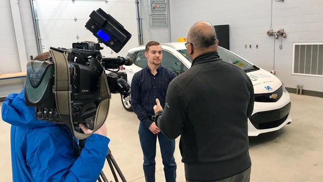 Kettering University Auto Drive Challenge team member Eric Smith speaks with anchor Mike Woolfolk and videographer Michael Japowicz about his role on the Bulldog Bolt team.{&nbsp;} (Photo: Kettering University)