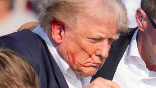 Republican presidential candidate former President Donald Trump is surrounded by U.S. Secret Service agents as he is helped off the stage at a campaign rally in Butler, Pa., Saturday, July 13, 2024. (AP Photo/Gene J. Puskar)