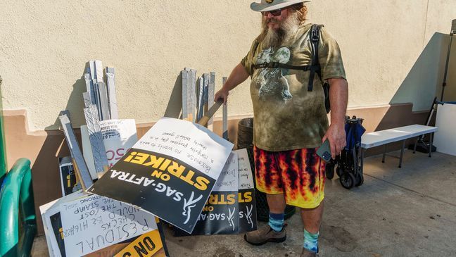 Actor Jack Black looks for a picket sign as he joins demonstrators outside the Paramount Pictures Studio in Los Angeles, Tuesday, Sept. 26, 2023. (AP Photo/Damian Dovarganes)