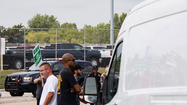 A City of Flint police officer approaches union members preventing cars from entering the General Motors Flint Assembly Plant as United Automobile Workers remain on strike against GM on Tuesday, Sept. 17, 2019, in Flint, Mich. GM and the union are negotiating at a time of troubling uncertainty for the U.S. auto industry. (Sara Faraj/MLive.com/The Flint Journal via AP)