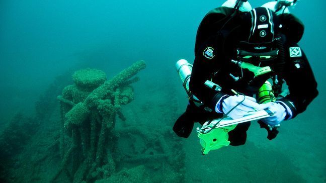 A researcher studies the shipwreck of the steam barge Messenger, which caught fire at a dock in Rogers City and was cut free and allowed to drift out into Lake Huron, where it finally sank about 4 miles offshore. Its burnt hull sits upright on the lake bottom with rudder, engine and anchors still in place. (National Oceanic and Atmospheric Administration)