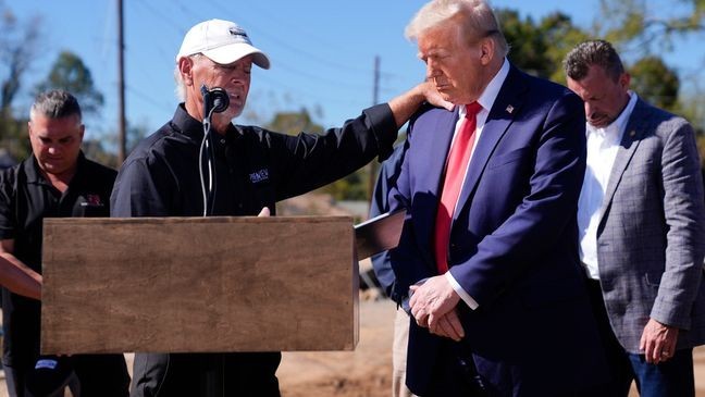 Republican presidential nominee former President Donald Trump prays with Mike Stewart, owner of Pine View Buildings, and others, after delivering remarks on the damage and federal response to Hurricane Helene, Monday, Oct. 21, 2024, in Swannanoa, N.C. (AP Photo/Evan Vucci)