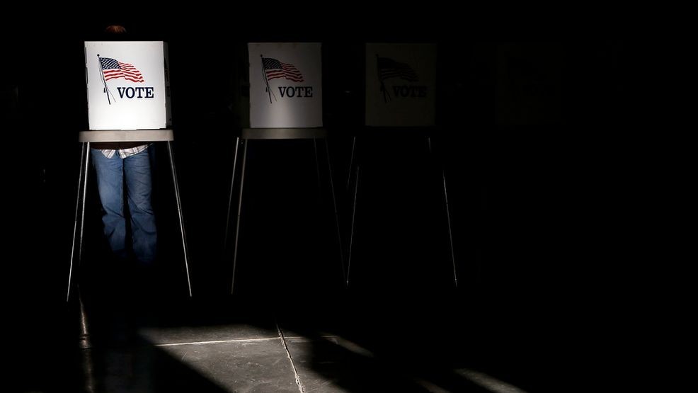 Voting booths are illuminated by a shaft of sunlight as people cast their ballots at a polling site in Billings, Mont., on Nov. 6, 2012. (AP Photo/Jae C. Hong, File)