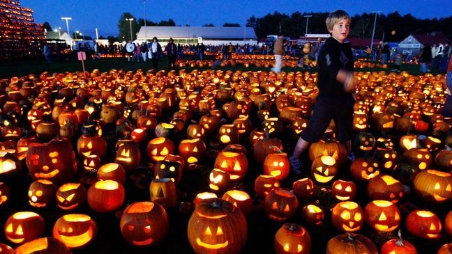 FILE - A boy finishes lighting a patch of jack-o-lanterns at the Camp Sunshine Maine Pumpkin Festival, Oct. 4, 2008, in Cumberland, Maine. (AP Photo/Robert F. Bukaty, File)