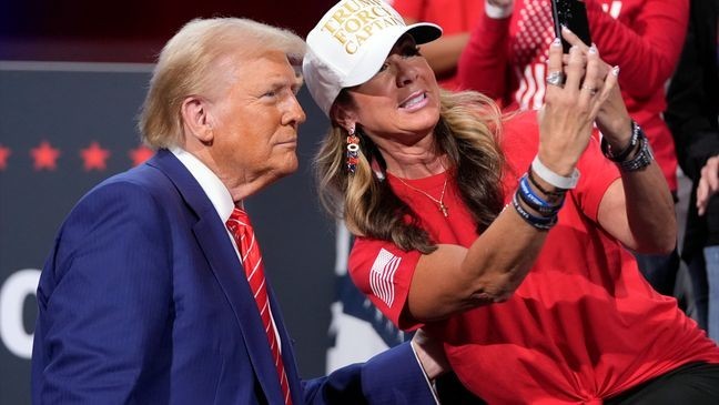 Republican presidential nominee former President Donald Trump poses for a photo with a supporter at a campaign event at the Cobb Energy Performing Arts Centre, Tuesday, Oct. 15, 2024, in Atlanta. (AP Photo/Alex Brandon)