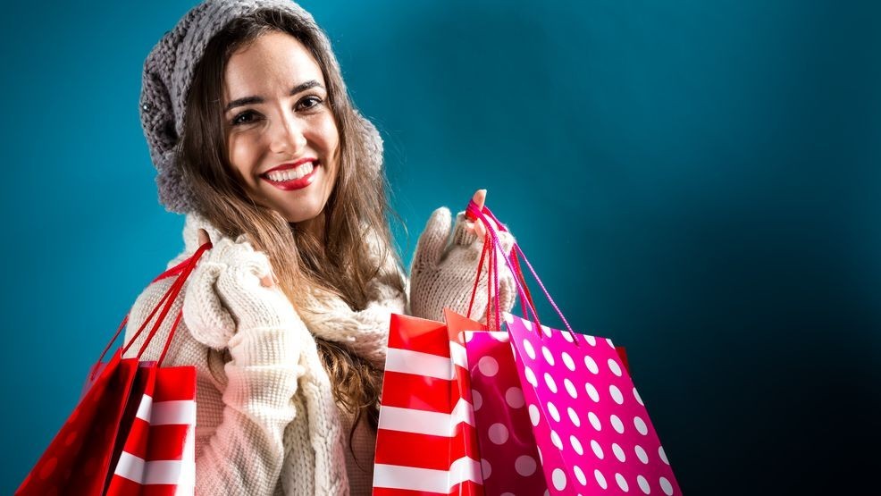 Happy young woman holding shopping bags on a blue background