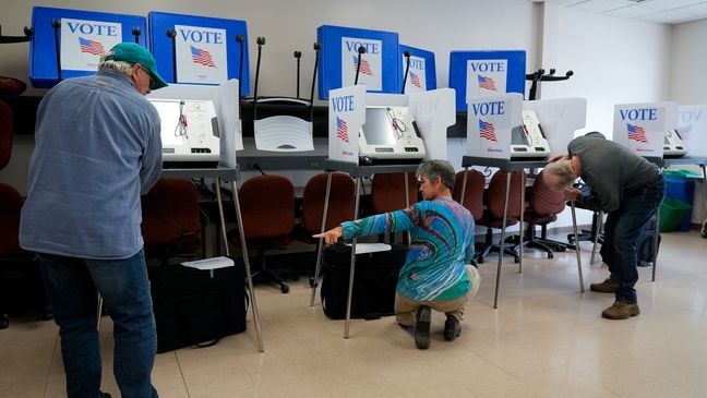 Poll workers set up ballot-marking machines at an early in-person voting site at Asheville-Buncombe Technical Community College, Wednesday, Oct. 16, 2024, in Marshall, N.C. (AP Photo/Stephanie Scarbrough)