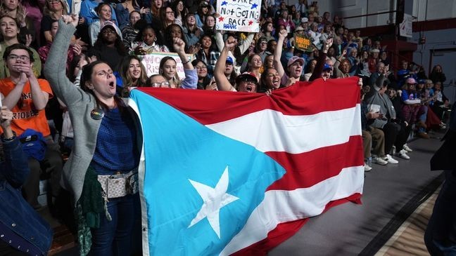 Attendees holding the flag of Puerto Rico cheer as Allentown, Pa. Mayor Matt Tuerk speaks during a campaign rally for Democratic presidential nominee Vice President Kamala Harris in Memorial Hall at Muhlenberg College in Allentown, Pa., Monday, Nov. 4, 2024. (AP Photo/Susan Walsh)