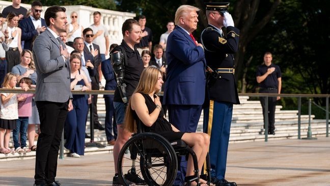 Marlon Bateman, left, former U.S. Marine Sgt. Tyler Vargas, former U.S. Marine Cpl. Kelsee Lainhart, center front, and Republican presidential nominee former President Donald Trump place their hands over their heart after placing a wreath at the Tomb of the Unknown Solider in honor of the 13 service members killed at Abbey Gate, at Arlington National Cemetery, Monday, Aug. 26, 2024, in Arlington, Va. (AP Photo/Alex Brandon)