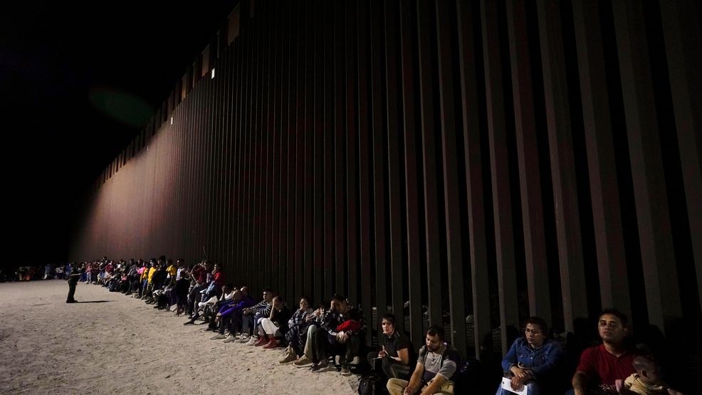 FILE - Migrants wait to be processed after crossing into the United States near the end of a border wall, on Aug. 23, 2022, near Yuma, Ariz. (AP Photo/Gregory Bull)