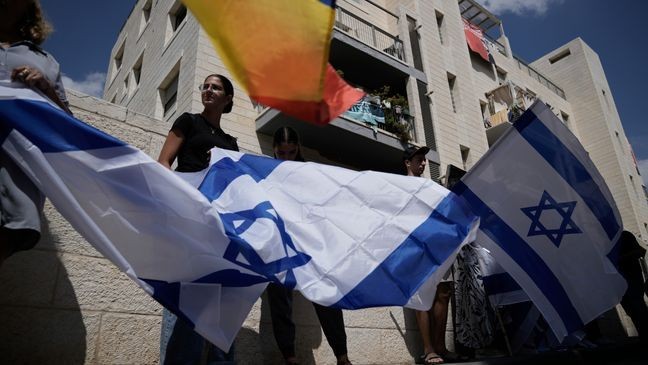 Mourners wave Israeli flags as they accompany the family of Israeli-American hostage Hersh Goldberg-Polin, who was killed in Hamas captivity in the Gaza Strip, on their way to his funeral in Jerusalem, Monday, Sept. 2, 2024. (AP Photo/Leo Correa)