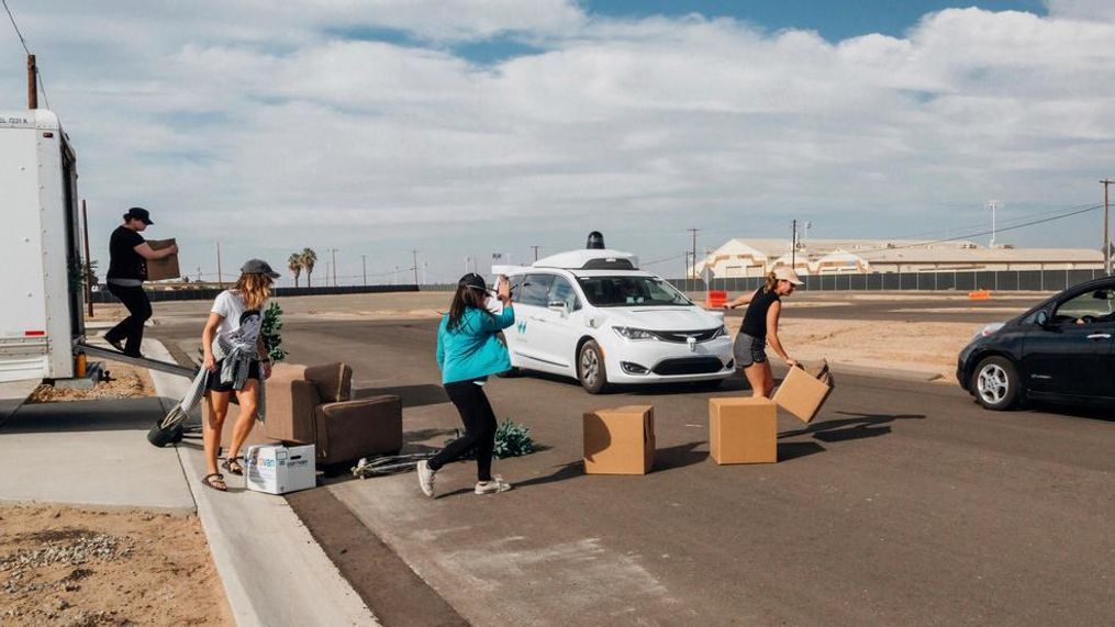 In this Sunday, Oct. 29, 2017, photo provided by Waymo, its employees place boxes as obstacles, staging "structured tests" for a white Chrysler Pacifica minivan, center, equipped with its self-driving car technology at a facility in Atwater, Calif. Waymo, hatched from a Google project started eight years ago, showed off its progress Monday during a rare peek at a closely guarded testing facility located 120 miles southeast of San Francisco where its robots complete their equivalent to driver's education. (Julia Wang/Waymo via AP)