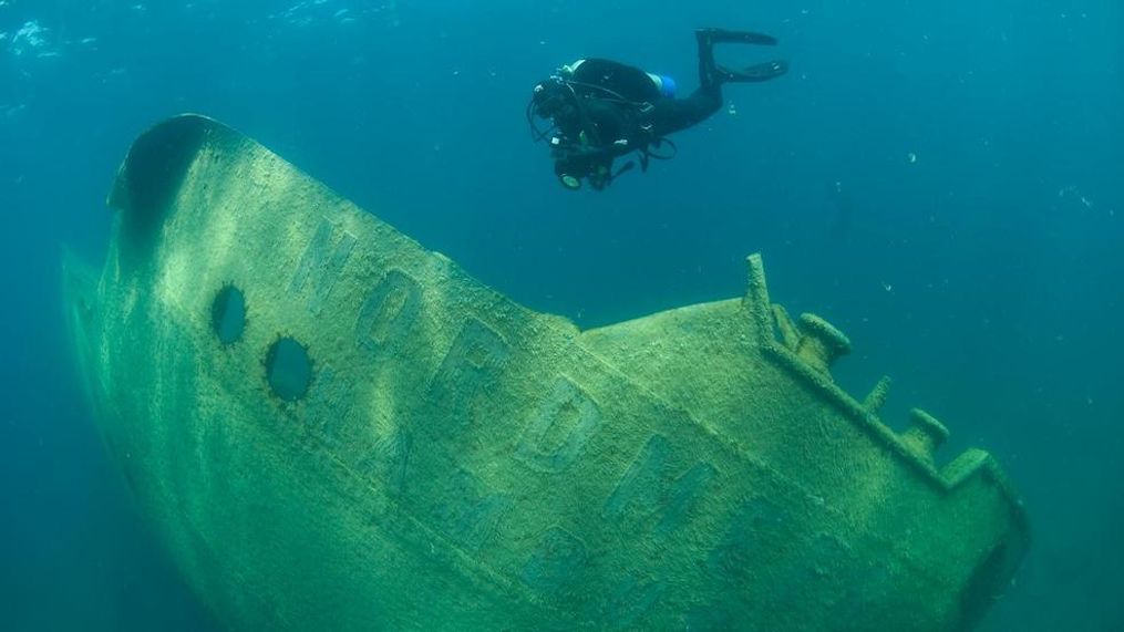 A diver at Thunder Bay National Marine Sanctuary near Alpena photographs the wreck of the German freighter Nordmeer, which met its end on Lake Huron in 1966. Part of the vessel stands out of the water, but years of storms and ice have broken and twisted the hull. (National Oceanic and Atmospheric Administration)