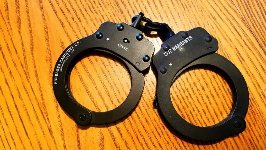 FILE - A pair of handcuffs with the words "Got Warrants" inscribed on them sit on a desk in this undated file photo. (Photo: Bangor Police Department)