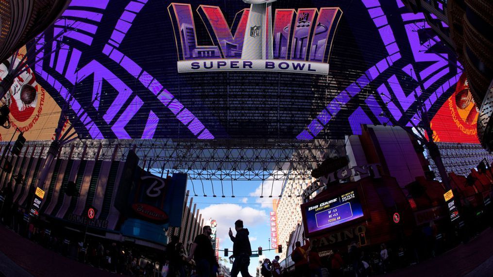 People cross a street at the Fremont Street Experience ahead of Super Bowl 58 Saturday, Feb. 10, 2024 in Las Vegas. The Kansas City Chiefs will play the NFL football game against the San Francisco 49ers Sunday. (AP Photo/Charlie Riedel)