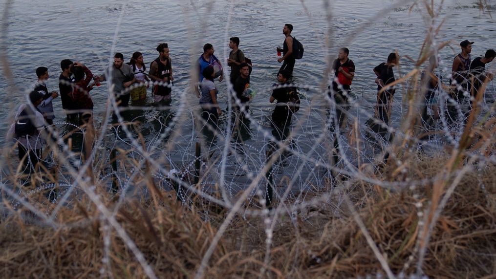 FILE - Migrants wait to climb over concertina wire after they crossed the Rio Grande and entered the U.S. from Mexico, Saturday, Sept. 23, 2023, in Eagle Pass, Texas. (AP Photo/Eric Gay, File)