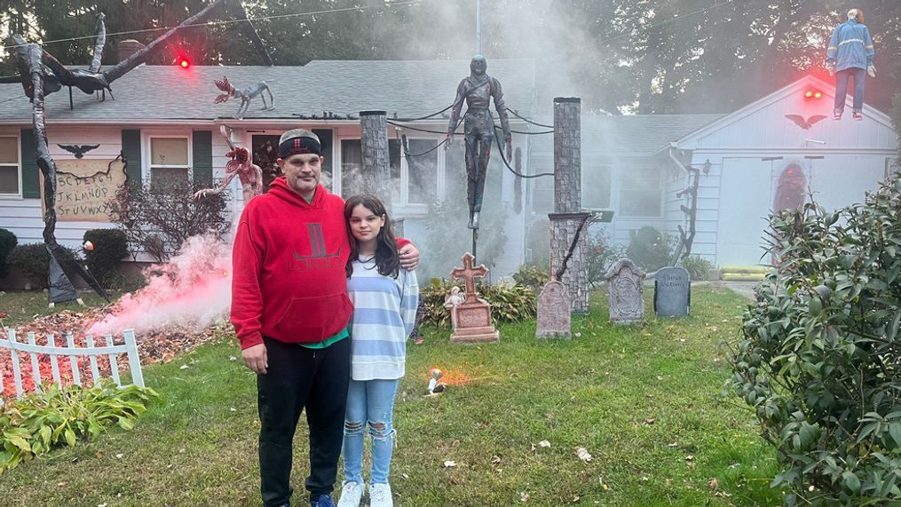 Steven Simoneau and his 11-year-old daughter, Isabella Simoneau, stand outside of their homemade "Stranger Things" Halloween display in North Providence, R.I. (WJAR)