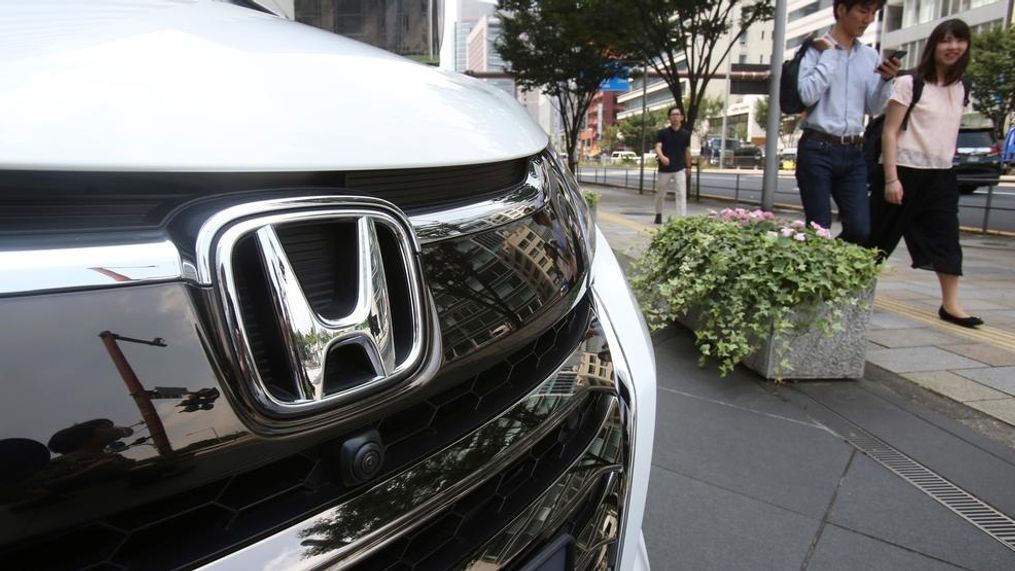 In this July 31, 2019, photo, people walk past a Honda car on display at Honda Motor Co. headquarters in Tokyo. Japanese automaker Honda reported Friday, Aug. 2, a 29% decline in fiscal first quarter profit as an unfavorable currency exchange and declining auto sales in the U.S. and India hurt earnings. (AP Photo/Koji Sasahara)