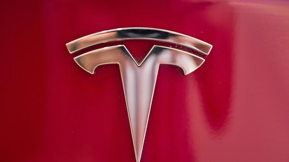 FILE - This Aug. 8, 2018, file photo shows a Tesla emblem on the back end of a Model S in the Tesla showroom in Santa Monica, Calif. Tesla is dropping two of the seven standard colors it had offered to customers to streamline production. In a tweet early Tuesday, Sept. 11, CEO Elon Musk said obsidian black and metallic silver will still be available, but at a higher cost. Tesla fans can still get solid black and “midnight silver metallic,” as well as pearl white, deep blue metallic and red as standard color choices. (AP Photo/Richard Vogel, File)