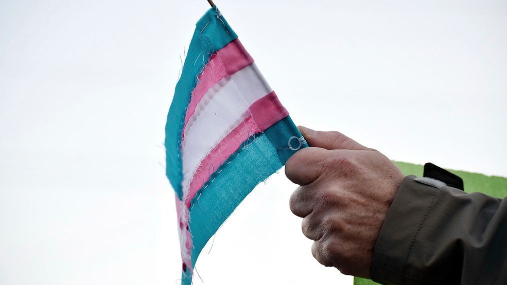 FILE - A person holds a transgender flag to show their support for the transgender community during the sixth annual Transgender Day of Remembrance at Maryville College, Nov. 20, 2016, in Maryville, Tenn. (Brianna Bivens/The Daily Times via AP, File)