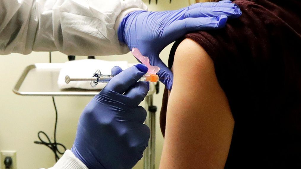 Pharmacist Michael Witte, left, gives Rebecca Sirull, right, a shot in the first-stage safety study clinical trial of a potential vaccine for COVID-19, the disease caused by the new coronavirus, Monday, March 16, 2020, at the Kaiser Permanente Washington Health Research Institute in Seattle. Sirull is the third patient to receive the shot in the study. (AP Photo/Ted S. Warren)