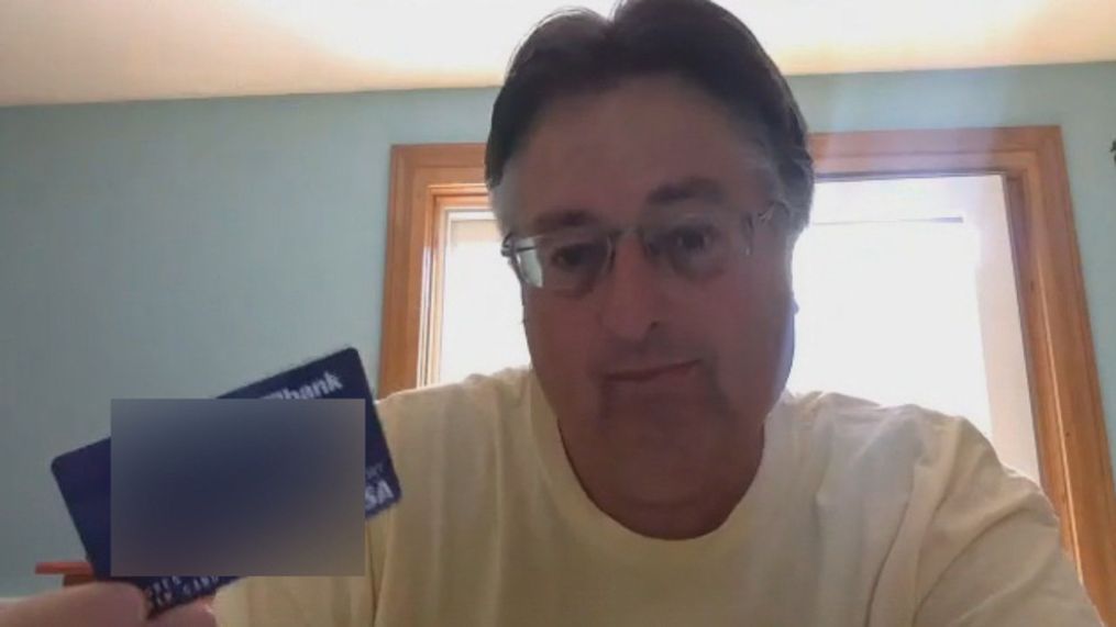 Greg Goan holding the debit card he received after someone filed for unemployment in his name (WGME).