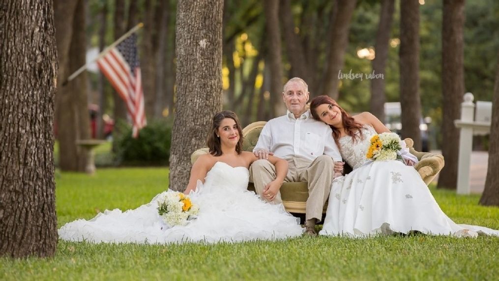 Twin sisters posing with their father, who is battling Alzheimer's, in donated wedding gowns because they know that he probably won't make it to their actual day (Lindsey Rabon Photography)