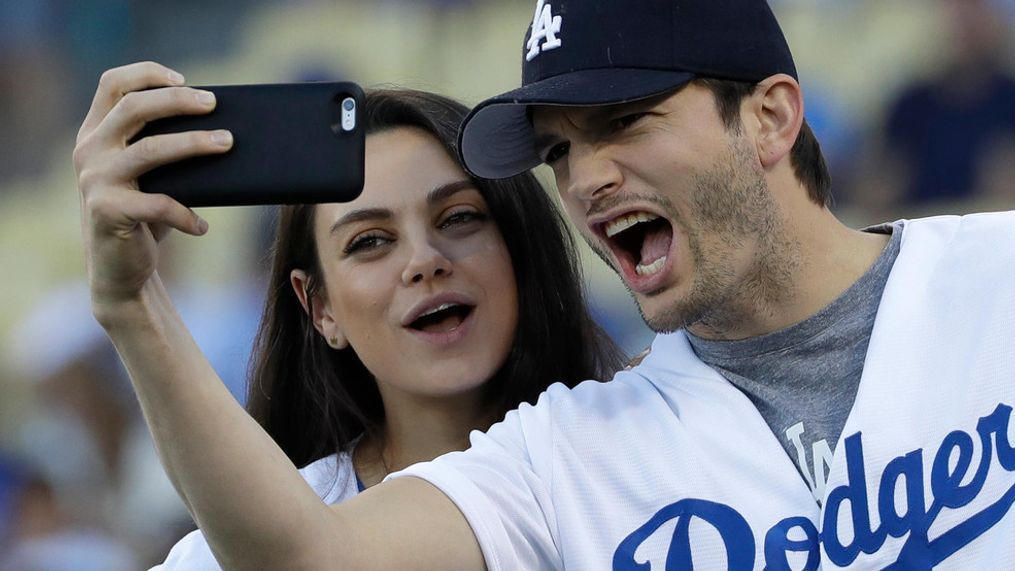 FILE- In this Oct. 19, 2016, file photo, Ashton Kutcher and wife Mila Kunis take a selfie before Game 4 of the National League baseball championship series between the Chicago Cubs and the Los Angeles Dodgers in Los Angeles. (AP Photo/David J. Phillip, File)