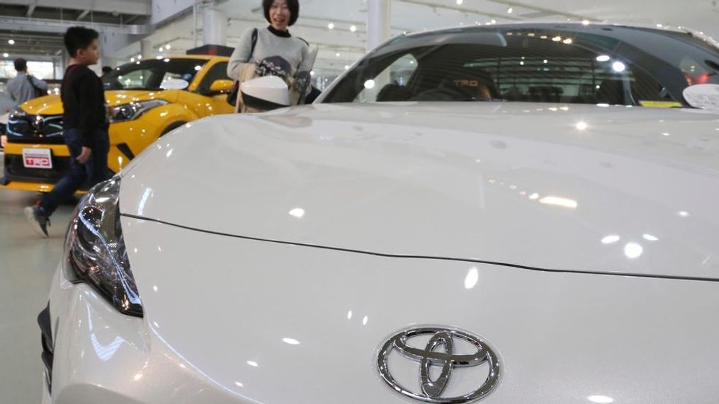 In this Nov. 13, 2017 photo, visitors take a look at a Toyota car at its showroom in Tokyo. Toyota plans to offer more than 10 purely electric vehicle models in its lineup by the early 2020s, marking the Japanese automaker's commitment to that growing technology sector.  Toyota Motor Corp. now offers no purely electric vehicles, although it leads in hybrid models, which switch between an electric motor and a gas engine. (AP Photo/Koji Sasahara)