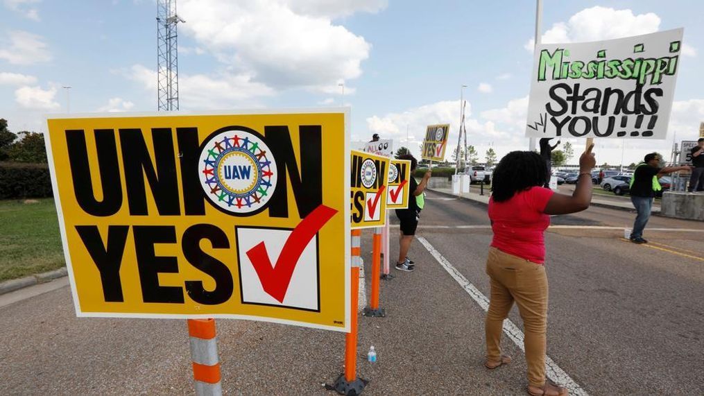 United Auto Workers  members and their volunteers stand outside an entrance to the Nissan vehicle assembly plant in Canton, Miss., and greet each arriving and departing vehicle, Thursday, Aug. 3, 2017. Union members set up informational lines outside employee entrances at the plant and greeted all shifts of workers reminding them to vote for the union. The vote for union representation of line workers runs Aug. 3-4. (AP Photo/Rogelio V. Solis)