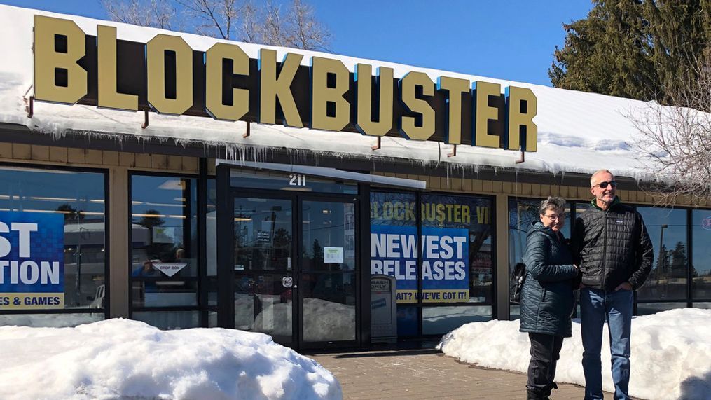 FILE - In this March 11, 2019, file photo Debby Saltzman, of Bend, Ore., poses for a photo, in front of the last Blockbuster store with her twin brother, Michael, visiting from Melbourne, Australia, in Bend, Ore. Taking the photo is Saltzman's husband, Jeremy Saltzman. The new Netflix movie called The Last Blockbuster that began airing March 15, 2021 is generating interest in the store, which became the last Blockbuster location on Earth when a location in Perth, Australia shut its doors in 2019. (AP Photo/Gillian Flaccus)