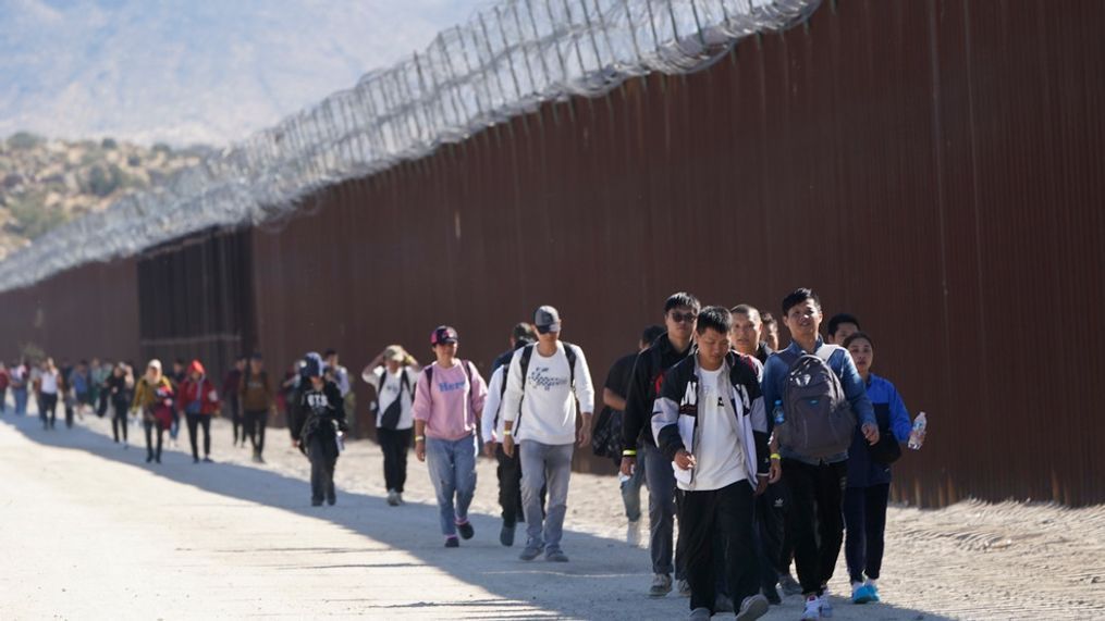 FILE - A group of people walk along the wall after crossing the border with Mexico to seek asylum, Oct. 24, 2023, near Jacumba, Calif. (AP Photo/Gregory Bull, File)