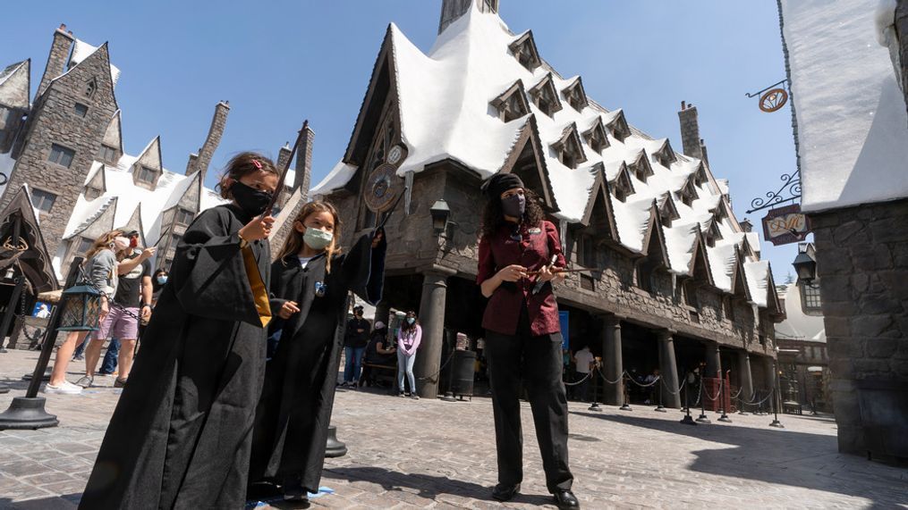 FILE - Campbell Chang, 6, and Juliana Single, 6, wear face masks as they cast their spells at Wizarding World of Harry Potter at Universal Studios Hollywood theme park in Los Angeles, on April 16, 2021. Warner Bros.{&nbsp;} (AP Photo/Damian Dovarganes, File)