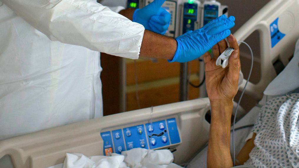 A healthcare worker high-fives a patient in the Covid-19 Unit at United Memorial Medical Center in Houston, Texas, July 2, 2020. - Despite its renowned medical center with the largest agglomeration of hospitals and research laboratories in the world, Houston is on the verge of being overwhelmed by cases of coronavirus exploding in Texas. (Photo by Mark Felix / AFP) / RESTRICTED TO EDITORIAL USETO GO WITH AFP STORY by Julia Benarrous: "Covid-19: Houston's hospital system underwater" (Photo by MARK FELIX/AFP via Getty Images)