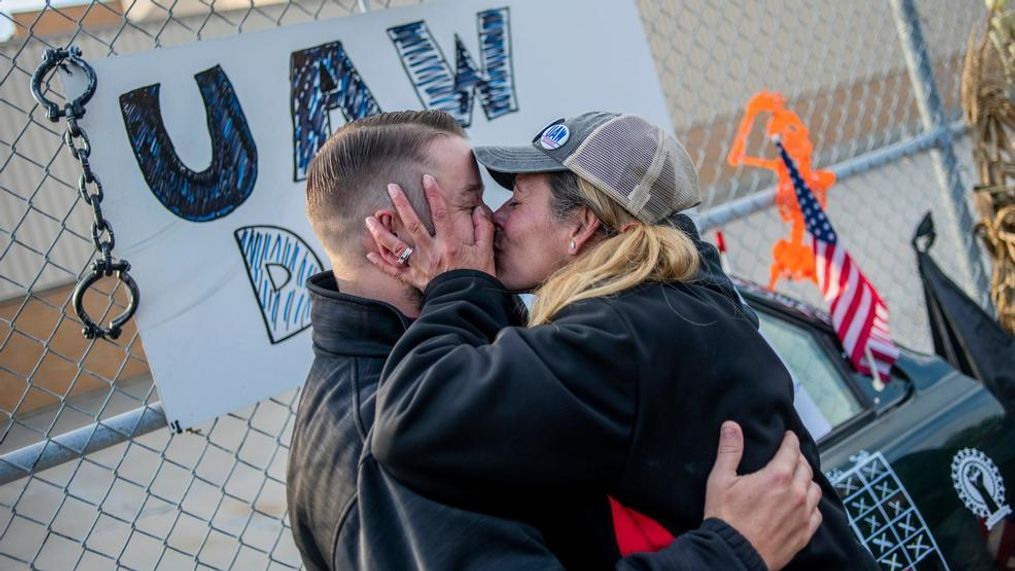 Clio resident Dawn Dekalita, 48, and a 16-year employee at the Flint Assembly Plant, plants a kiss on Shop Committee's Dustin Culhane in celebration as the United Auto Workers strike against General Motors comes to an emotional close outside of the Flint Assembly Plant, Friday, Oct. 25, 2019, in Flint, Mich. Striking General Motors factory workers are putting down their picket signs after approving a new contract that will end a 40-day strike that paralyzed the company's U.S. production. (Jake May/MLive.com/The Flint Journal via AP)