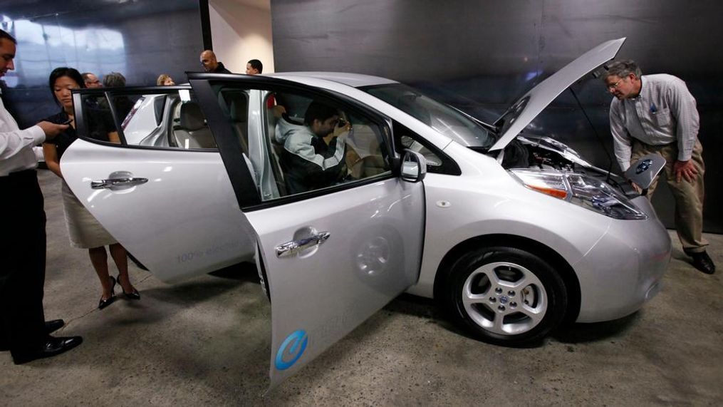 In this 2010 file photo, employees and guests look over a new Nissan Leaf, an all-electric vehicle, after a ribbon-cutting ceremony for a new car dealership in Seattle. Washington state's sales tax exemption for electric vehicles is expected to end sometime this summer after efforts to extend the tax break stalled during the recent legislative session. (AP Photo/Elaine Thompson, File)