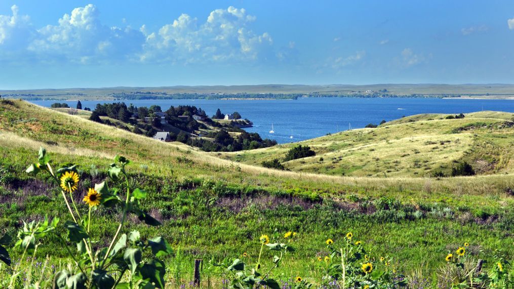 Rolling Nebraska grassland slopes down to the blue Lake McConaughy in Nebraska.