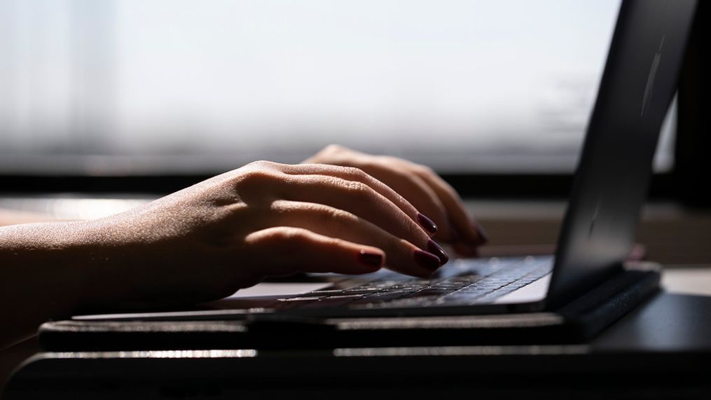 FILE - A woman types on a laptop while on a train in New Jersey, May 18, 2021. (AP Photo/Jenny Kane, File)