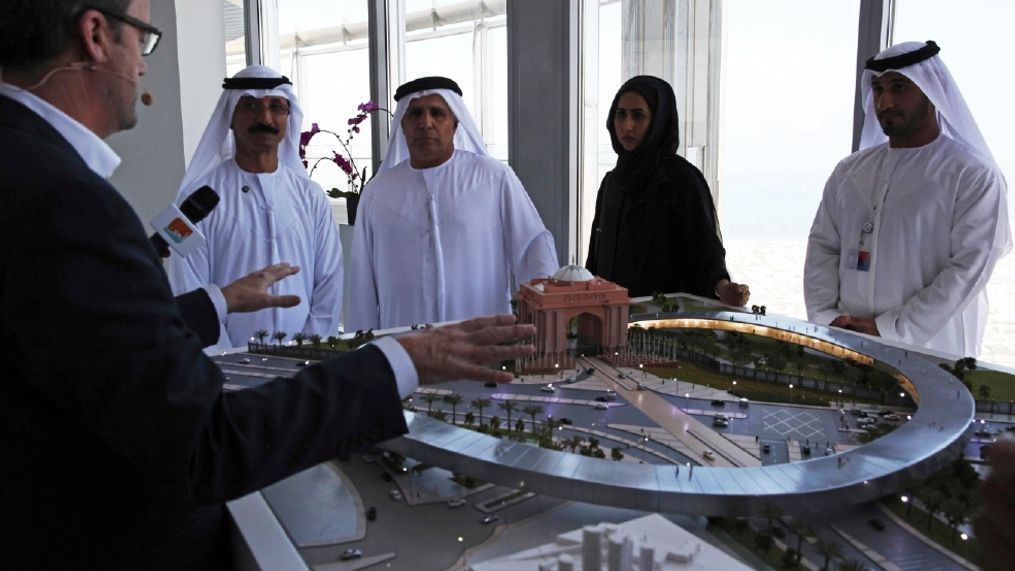 Rob Lloyd, the CEO of Hyperloop One, left, shows a model to Emirati officials including Mattar al-Tayer, the director-general and chairman of Dubai's Roads & Transport Authority, third left, in Dubai, United Arab Emirates, Tuesday, Nov. 8, 2016. The futuristic city-state of Dubai announced a deal on Tuesday with Los Angeles-based Hyperloop One to study the potential for building a line linking it to the Emirati capital of Abu Dhabi. (AP Photo/Jon Gambrell)