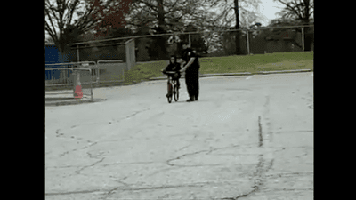 Image for story: WATCH: Police officer helps child learn to ride bicycle 