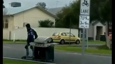 Image for story: Meals on wheels: Skateboarder tows barbecue down street 