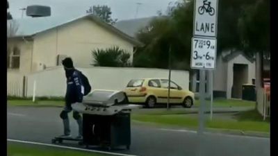 Image for story: Meals on wheels: Skateboarder tows barbecue down street 