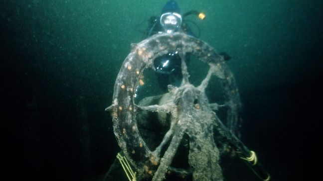 Jeri Baron Feltner and her husband Chuck Feltner, both divers, historians and authors, discovered the wreck of the Sandusky just west of the Mackinac Bridge in 1981. She is shown here at the ship’s wheel. (Dan Friedhoff)