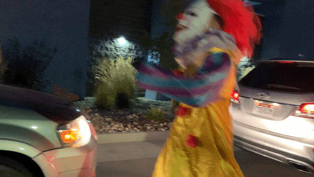 A clown gallops through a line of cars waiting to enter the haunted tunnel at the Orem Wiggy Wash location. (Adam Forgie, KUTV){p}{/p}