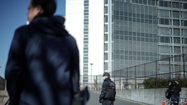 FILE - In this Jan. 11, 2019, file photo,  a security official, center, stands guard in front of Tokyo Detention Center, where former Nissan chairman Carlos Ghosn is detained, in Tokyo.{&nbsp;} (AP Photo/Eugene Hoshiko, File)