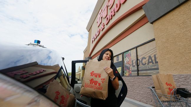 Fry's customer service representative Yuri Alvarado puts groceries into the self-driving Nuro vehicle parked outside a Fry's supermarket, which is owned by Kroger, as part of a pilot program for grocery deliveries Thursday, Aug. 16, 2018, in Scottsdale, Ariz. Kroger Co. has chosen the Phoenix suburb as a test market for delivering groceries using driverless cars. (AP Photo/Ross D. Franklin)