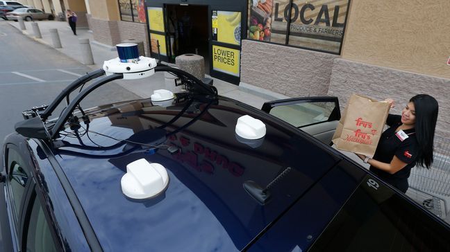 Fry's customer service representative Yuri Alvarado puts groceries into the self-driving Nuro vehicle parked outside a Fry's supermarket, which is owned by Kroger, as part of a pilot program for grocery deliveries Thursday, Aug. 16, 2018, in Scottsdale, Ariz. Kroger Co. has chosen the Phoenix suburb as a test market for delivering groceries using driverless cars. (AP Photo/Ross D. Franklin)