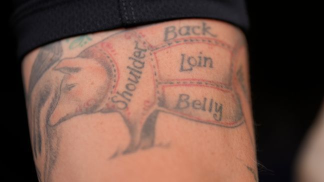 George Logue, pit master for The Shed BBQ and Blues Joint team, shows his pig tattoo at the World Championship Barbecue Cooking Contest, Friday, May 17, 2024, in Memphis, Tenn. (AP Photo/George Walker IV)