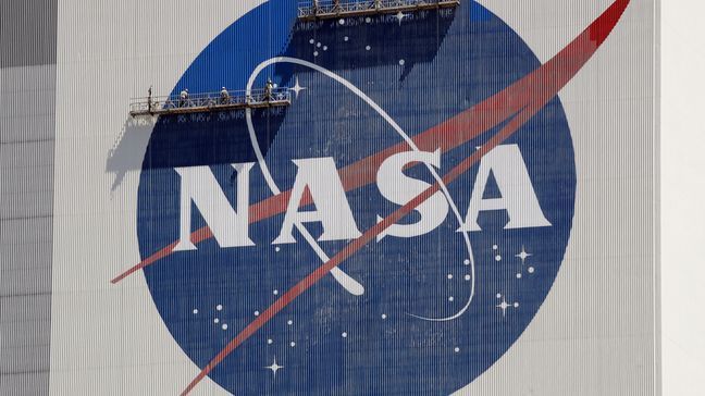 FILE - Workers on scaffolding repaint the NASA logo near the top of the Vehicle Assembly Building at the Kennedy Space Center in Cape Canaveral, Fla., May 20, 2020.  (AP Photo/John Raoux, File)